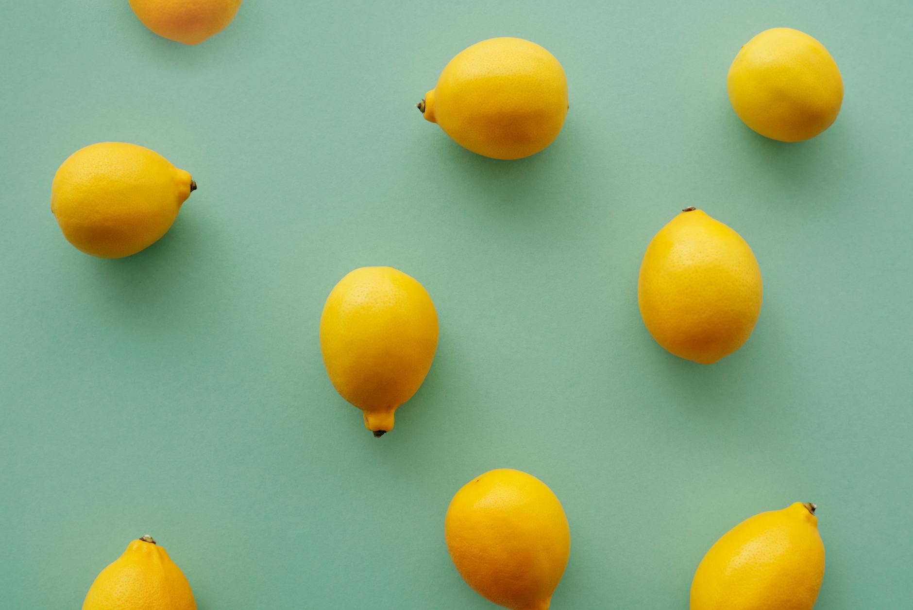 A hand holding a fresh lemon against a vivid yellow background, symbolizing freshness and renewal after distance.