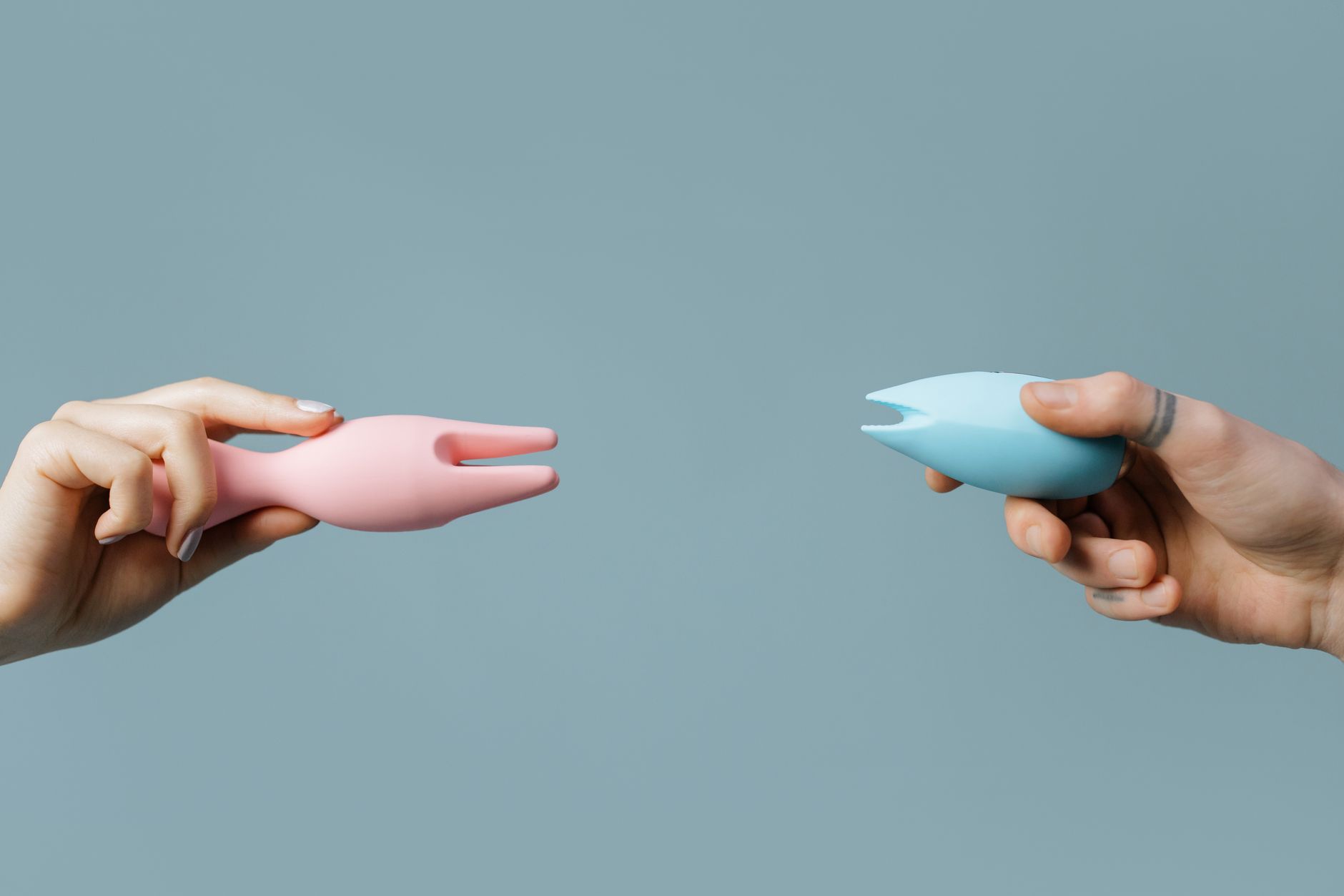 Hands holding pastel-colored silicone toys against neutral background