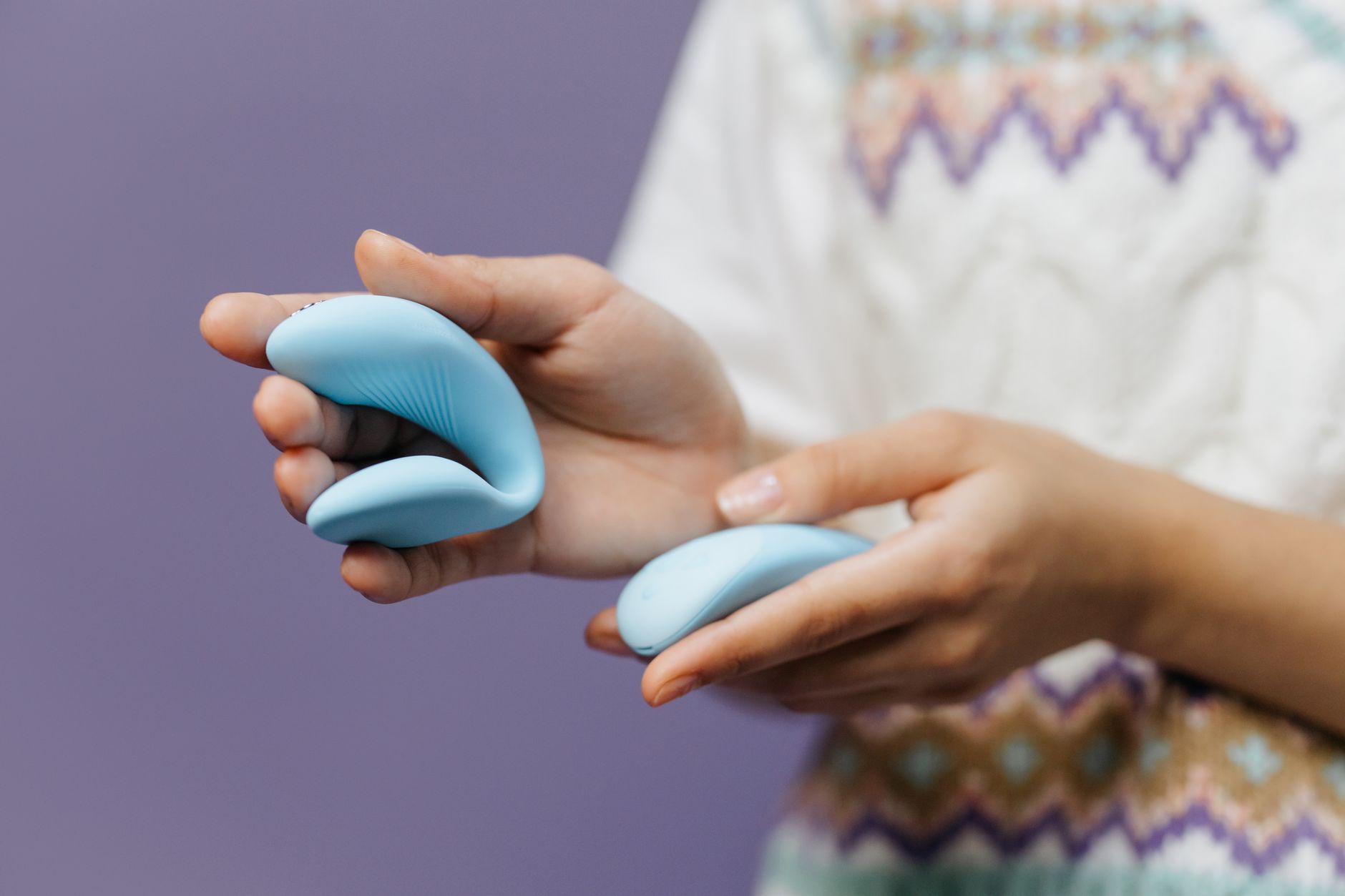 Close-up of hands holding a sleek vibrator, representing the importance of comfort and care during intimate moments.