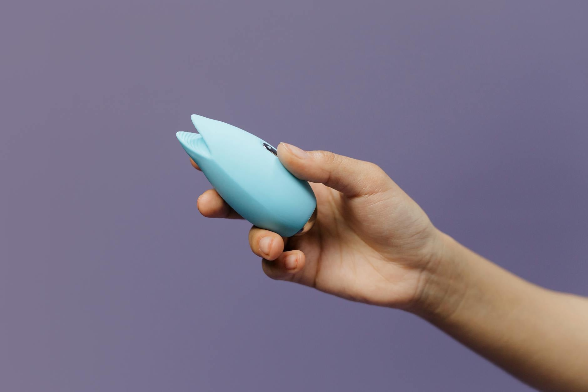 A vibrant clitoral vibrator held in hand, representing self-knowledge and sexual confidence in new relationships